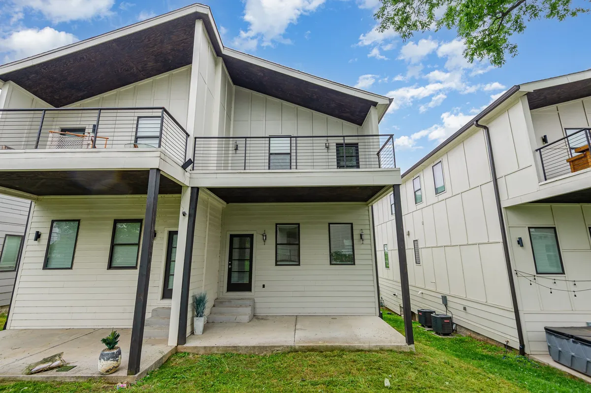 An exterior view showcasing the modern building architecture and spacious balconies overlooking a green lawn. The balconies offer private outdoor space for fresh air and relaxation, seamlessly connecting the indoors with the outdoors.