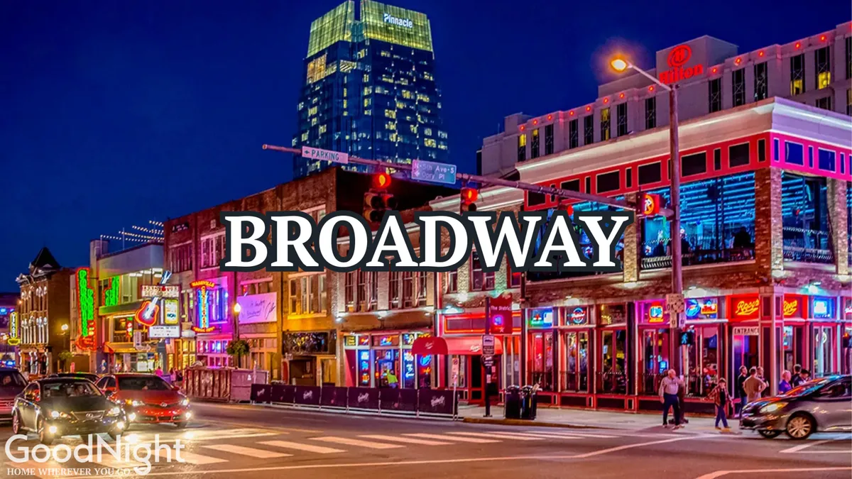 This dynamic image captures neon signs blazing over a busy Nashville street. Colorful storefronts line the street, people walk along the sidewalks, and tall buildings rise in the background, creating a palpable sense of excitement and energy. The overall scene exudes the vibrant nightlife and entertainment options that define downtown Nashville, especially the Broadway district mentioned in the section.