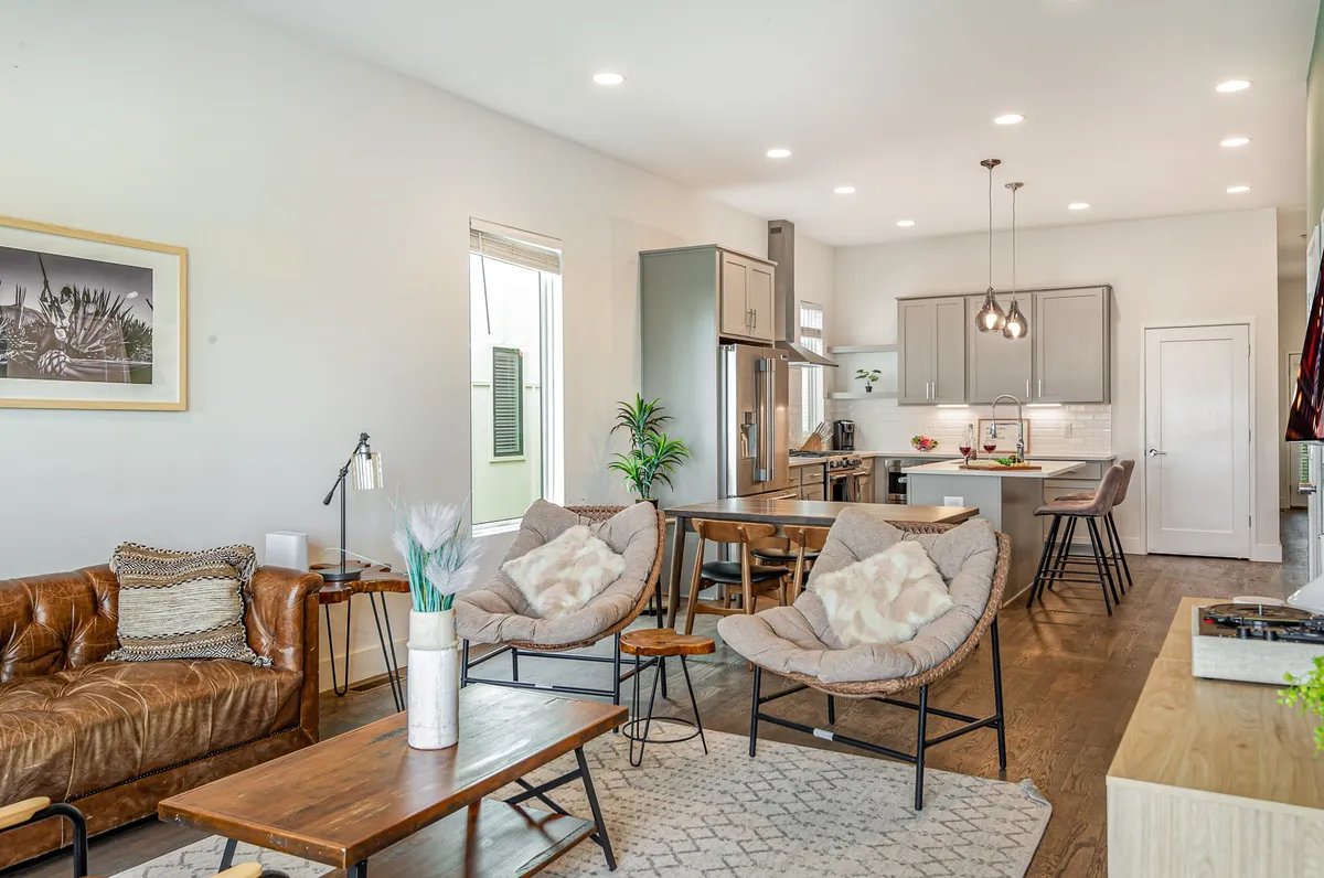 A spacious open-concept interior that blends a leather sofa, stylish chairs, a dining table, and an open kitchen area. The layout encourages seamless interaction between living, dining, and kitchen spaces—ideal for hosting and casual gatherings.
